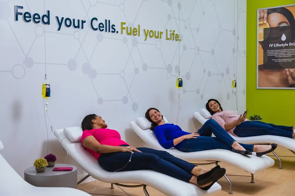 Three clients relaxing in The DRIPBaR lounge receiving IV therapy